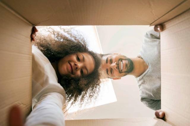 A man and young girl look inside a box.